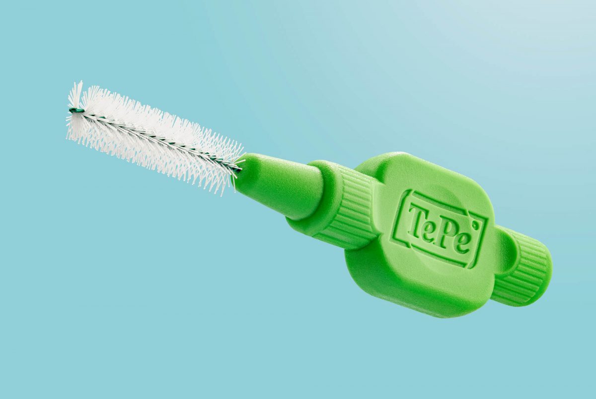 TePe close-up tooth brush. Green product and colorful background.